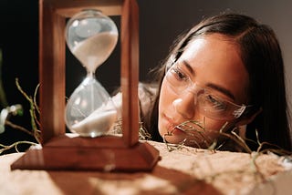 woman looks at a sand hourglass.