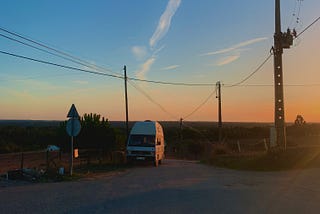 A vintage Volkswagen caravan parked on a road at sunset in the Portuguese countryside
