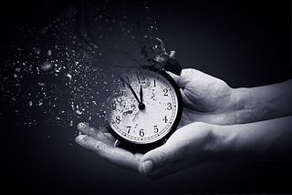 Two hands holding a dissolving small clock
