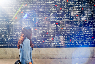A woman looking at the Wall of Love located in Paris, France.