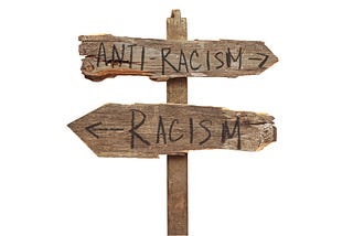 a rustic wooden signpost with an arrow pointing backwards to racism and forwards to anti-racism