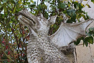 A stone statue of a sitting dragon, its snout turned to the sky.