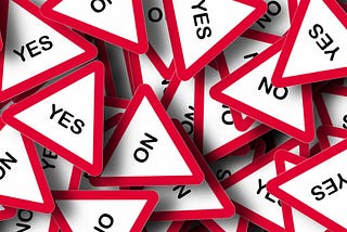 A pile of red and white triangle signs that read either “yes” or “no.”