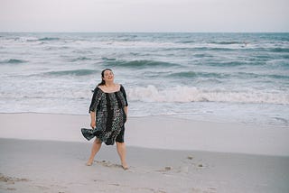 Author standing on a beach and laughing