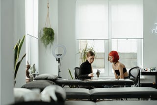 A tattooer and her client discussing details of tattoo project in the creator’s studio