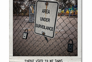 The sign on the chain link fence says “area under surveilance”