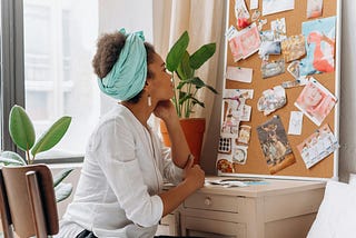 Woman in white top looking at a corkboard