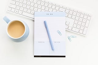 A light blue to-do list with a pen, keyboard and coffee mug