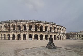 The ancient Roman arena of Nimes, France, with a statue of a matador spreading his cape outside.