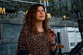 Woman on an outdoor stage holding a microphone.