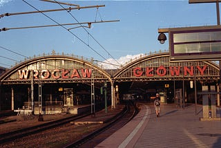 Wroclaw train station. A man walking along the platform. Overhead wires.