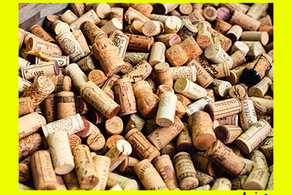 A large pile of wine corks on a bright yellow background