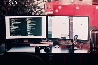 two black computer monitors on black table