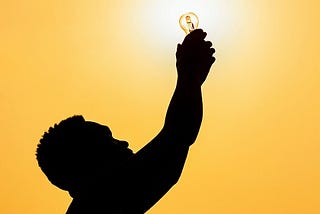 A man holding a light bulb up in the air.