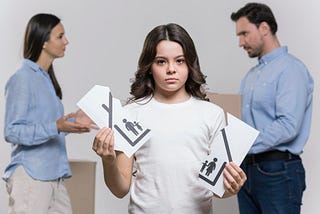 A young girl standing alone, visibly heartbroken, as she tears a family photo in half, symbolizing the deep pain caused by her parents’ frequent arguments