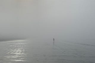 Foggy morning on a beach, figure in the distance