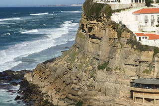 Whitewashed houses lining a dramatic cliff above the Mediterranean sea
