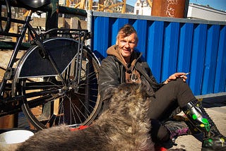 homeless man sitting on curb with bicycle and dog