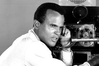The actor Harry Belafonte poses in front of a vintage recording device.