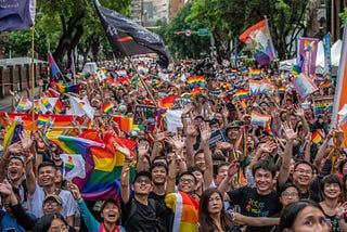 Demonstrators waving rainbow flags and smiling