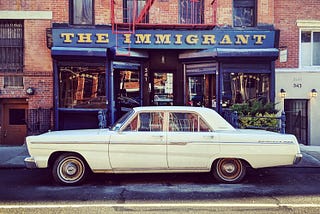 A classic car parked in front of the Immigrant wine and beer bar