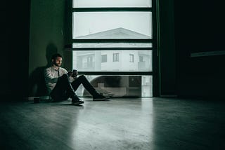 A man on a mobile phone in a dark room. Don’t let doomscrolling derail you.