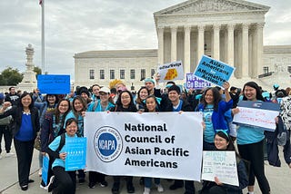 Group photo of members of the National Council of Asian Pacific Americans and their banner and logo, in front of the Supreme Court on Monday, October 31, 2022.