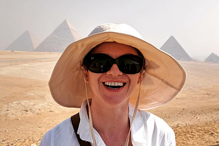 a woman smiling in front of the Great Pyramids of Giza
