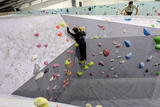 Two climbers on a section of an indoor bouldering gym