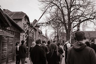 Auschwitz, Poland — March 23, 2023: A black and white photo of a group of visitors at the entrance of Auschwitz Museum, the site of the former Nazi concentration camp.