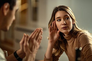 Young displeased woman ignoring her boyfriend who is begging for forgiveness