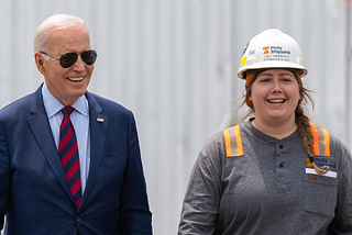 Joe Biden, in his aviator sunglasses, standing with a construction worker.