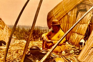 A native Indian woman sitting in front of her floating home on Lake Titicaca, Bolivia