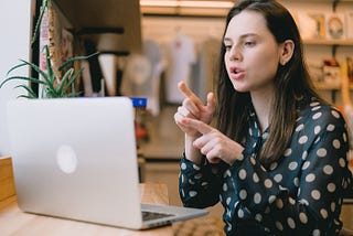 Young woman uses sign language to communicate over her laptop.