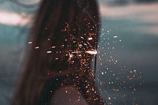 back of a woman holding a sparkling fire work