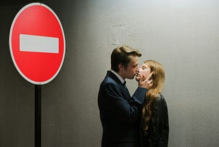 A man kissing a woman under a ‘No Entry’ sign