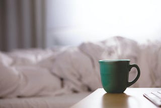 Hot steaming coffee cup on nightstand