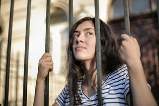 Young woman trapped behind prison bars