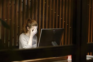 Woman rubbing her forehead in front of a computer