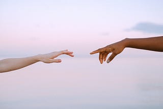 Two hands reaching for one another, each with a finger extended.