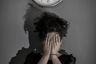 A person standing beneath a clock with their hands covering their face in anguish. The clock’s numbers and hands are distorted