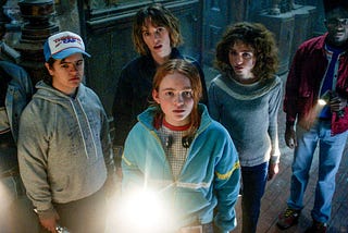 The Hawkins kids gather around a flashlight in Stranger Things Season Four