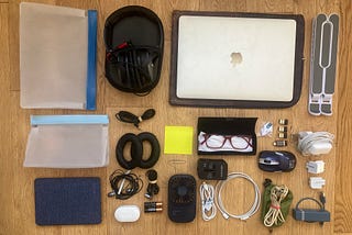 Tech gear arranged on wood floor. Many electrical gadgets including a laptop and headphones.