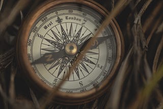 Old “West London”, bronze compass laying in dried grass