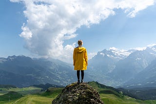 A woman standing on a hill overlooking a mountain range.