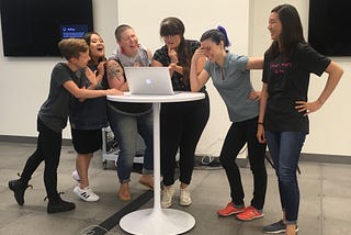 Six Bridge School students laughing around a laptop as they set up a presentation