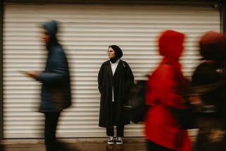 Image of a Muslim woman waiting on a busy streetscape.