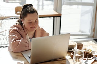A girl with down syndrome using a laptop for her day today activities.