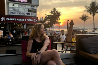 Image of Author sitting on a restaurant patio with the sunset in the background.