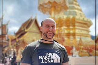 A photograph of me candidly smiling. Behind me is the famous giant gold pagoda found at Wat Phra That Doi Suthep (temple).